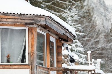 Wooden cottage with snowy roof. Winter vacation