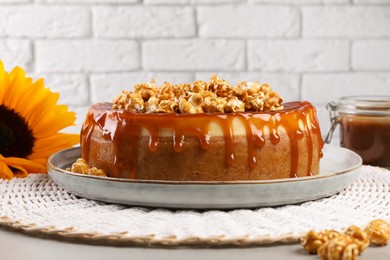 Photo of Delicious cheesecake with caramel and popcorn on light grey table