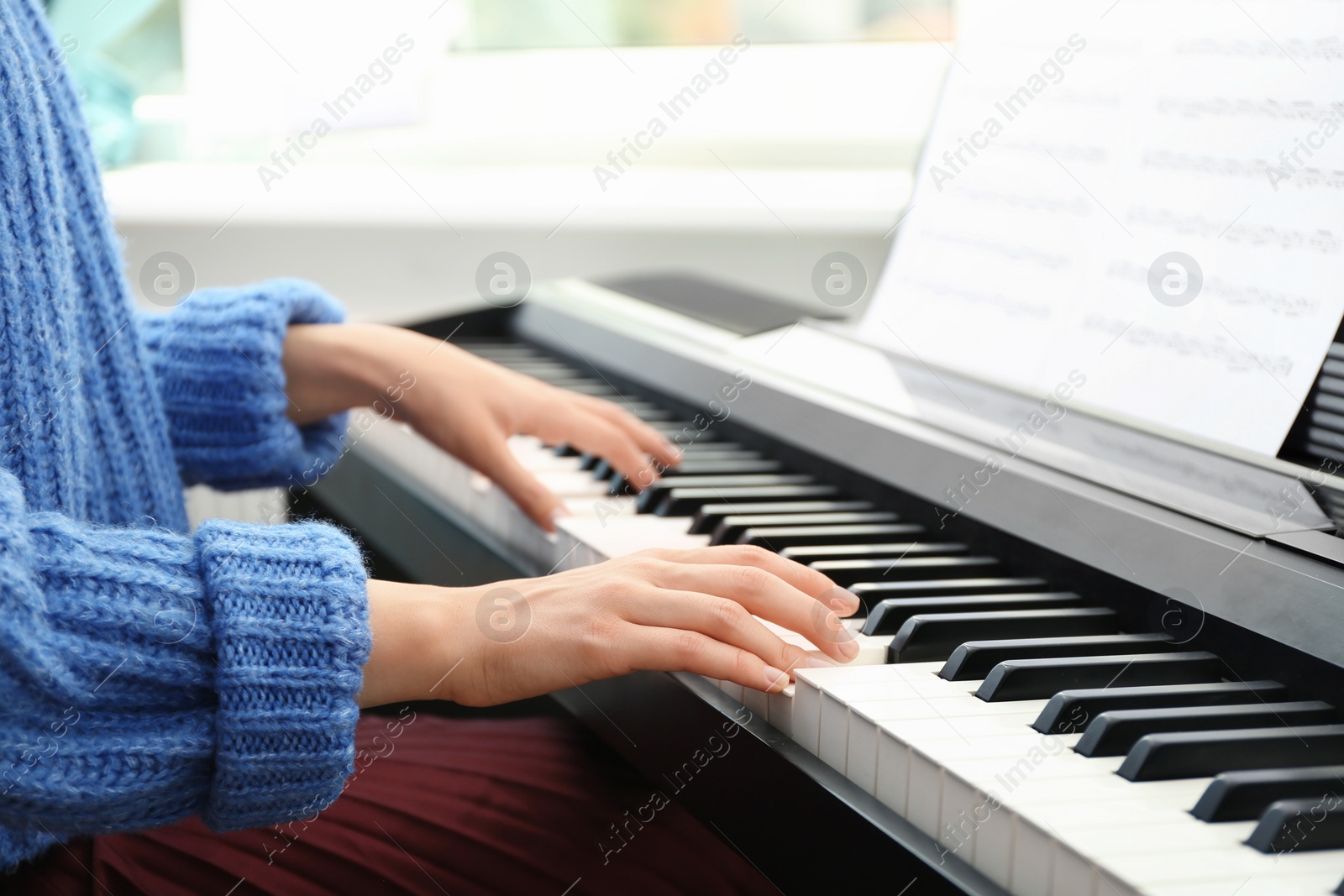 Photo of Young woman playing piano at home, closeup