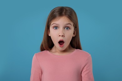Portrait of surprised girl on light blue background