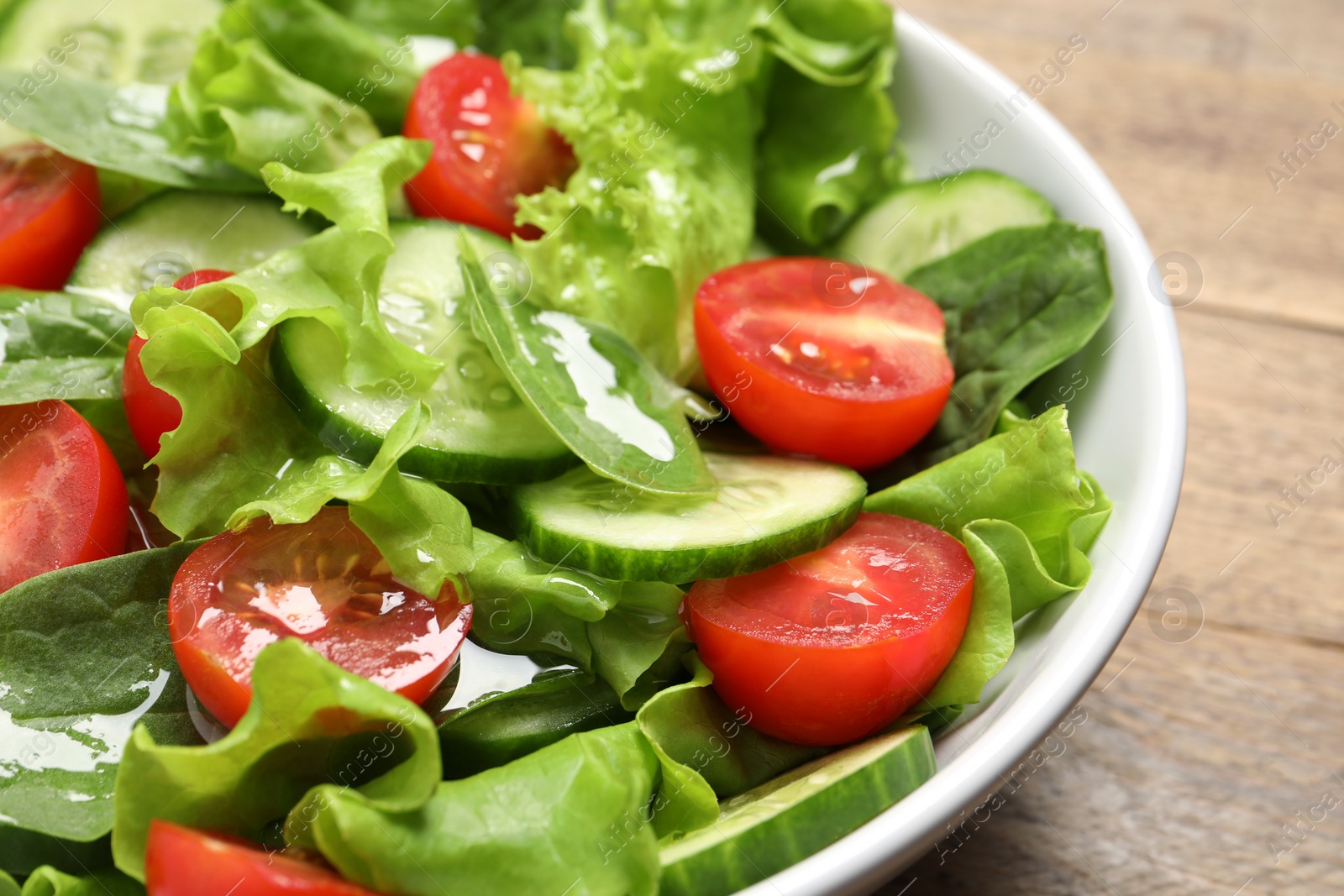 Photo of Delicious vegetable salad on wooden table, closeup