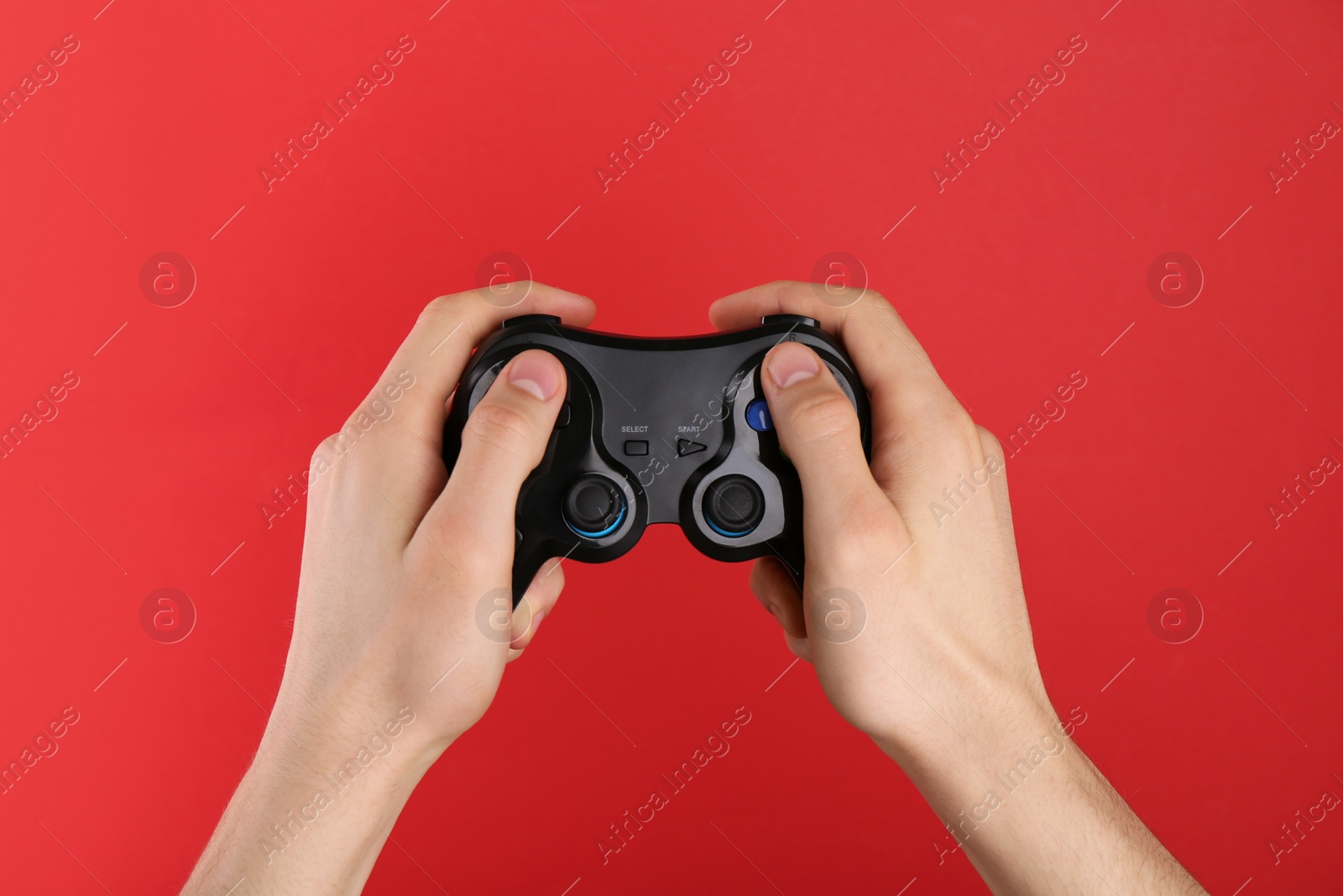 Photo of Man using wireless game controller on red background, closeup