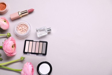 Photo of Flat lay composition with different makeup products and beautiful spring flowers on gray background, space for text