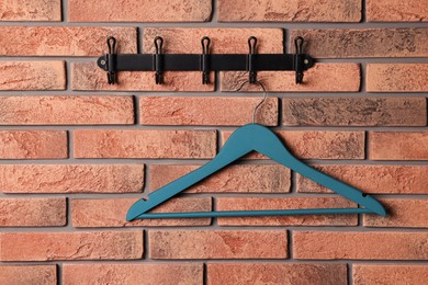 Photo of Hook rack with blue clothes hanger on red brick wall