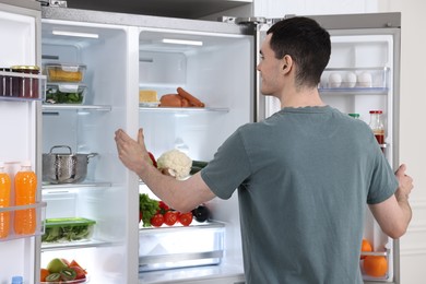 Happy man near refrigerator in kitchen at home