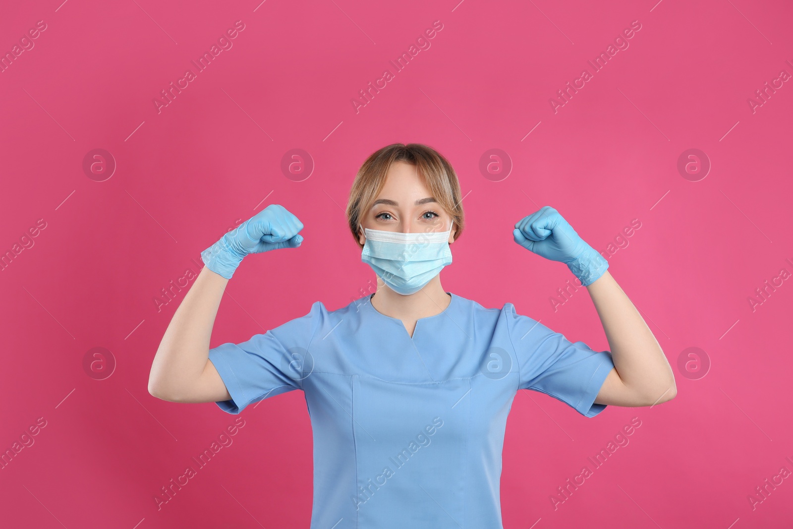 Photo of Doctor with protective mask showing muscles on pink background. Strong immunity concept