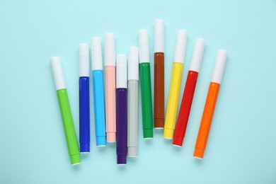 Different colorful markers on light blue background, flat lay