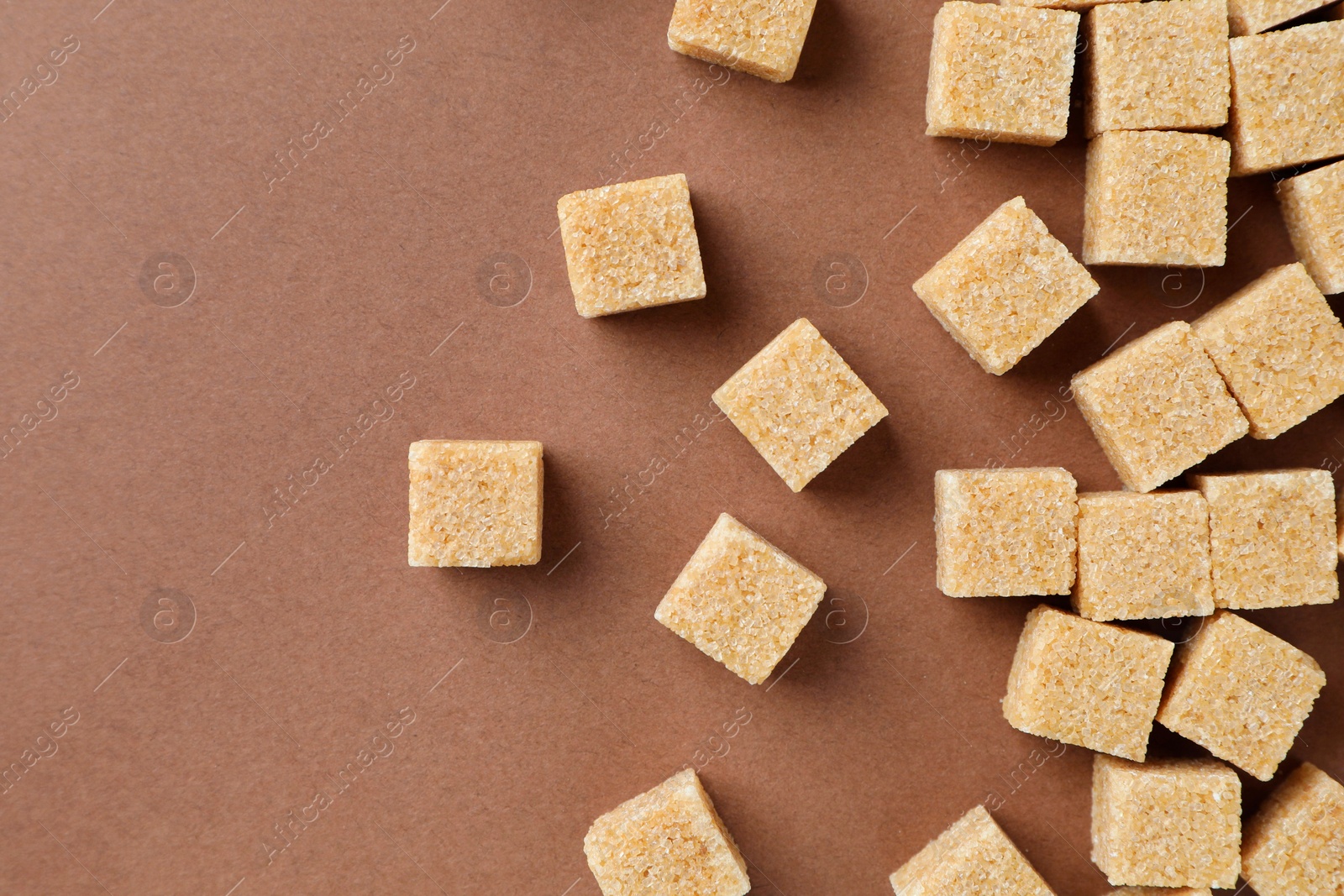 Photo of Brown sugar cubes on color background, top view