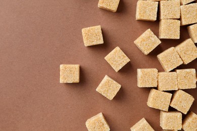 Brown sugar cubes on color background, top view