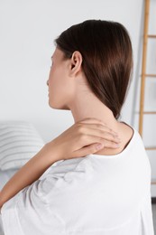 Woman suffering from neck pain in room