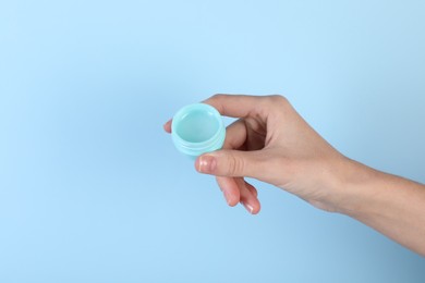 Photo of Woman with lip balm on light blue background, closeup