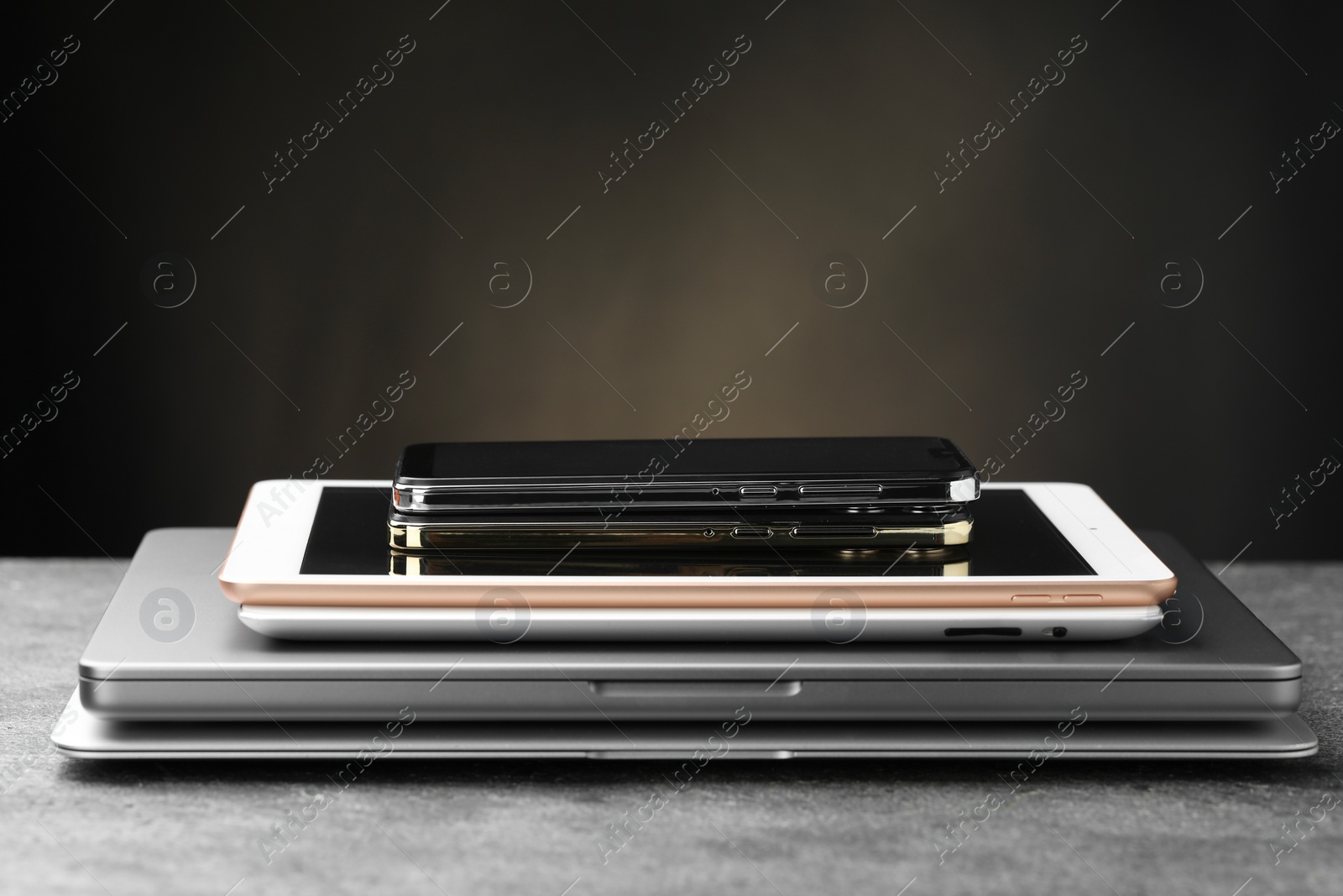 Photo of Stack of electronic devices on grey table, closeup. Space for text