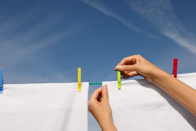 Photo of Woman putting clothes pins on laundry line outdoors, closeup. Space for text