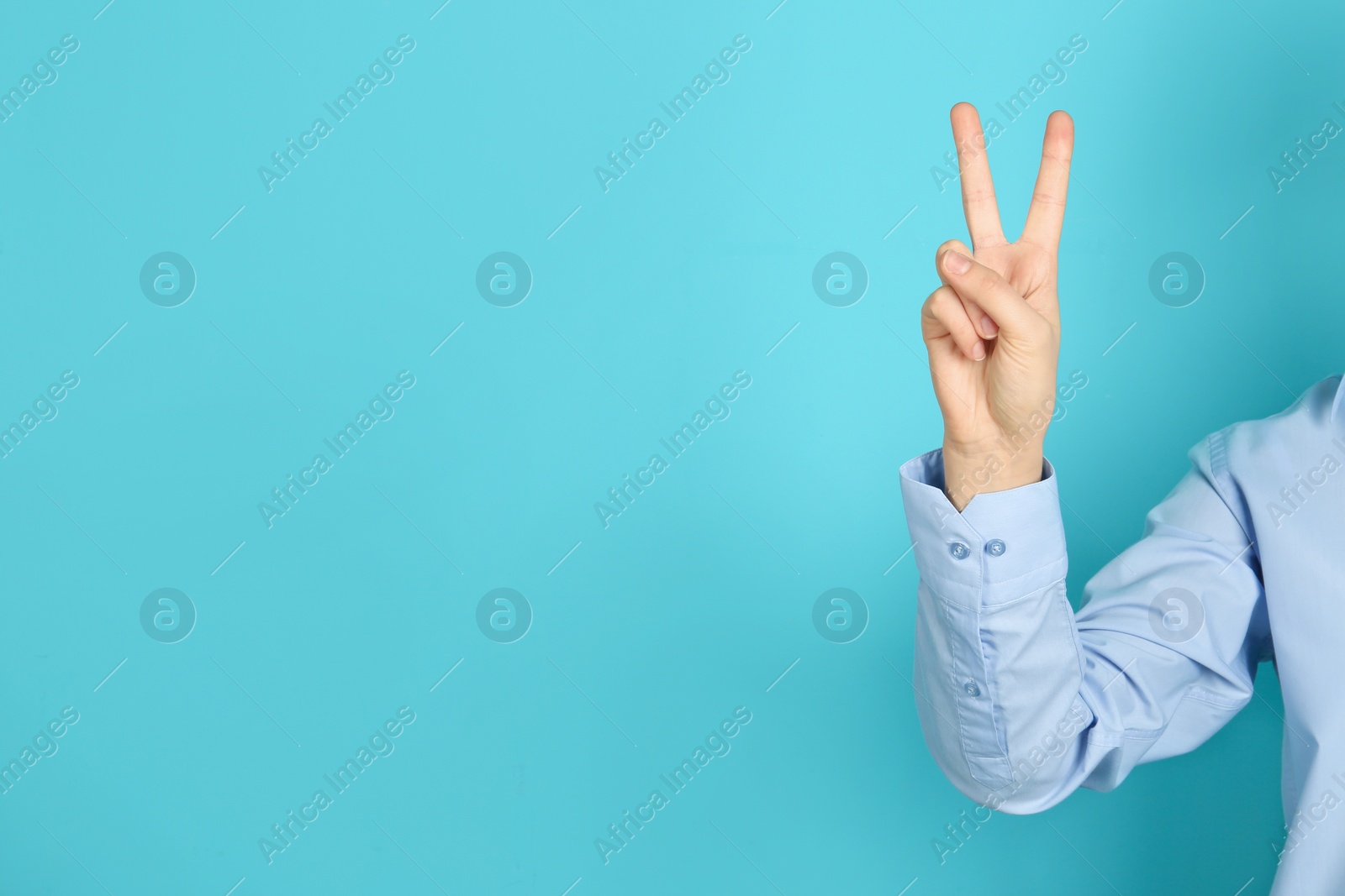 Photo of Young woman showing victory gesture on color background. Space for text