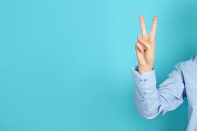 Young woman showing victory gesture on color background. Space for text