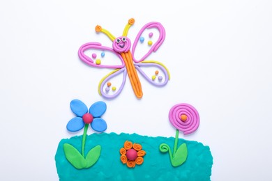 Photo of Butterfly and flowers made of plasticine on white background, top view