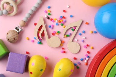 Baby song concept. Wooden notes, kids maracas and toys on pink background, flat lay