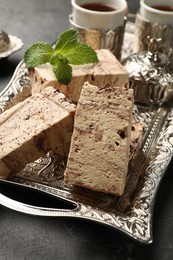 Photo of Tasty chocolate halva and mint on black table