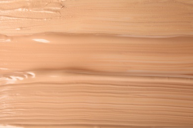 Photo of Samples of different foundation shades as background, top view