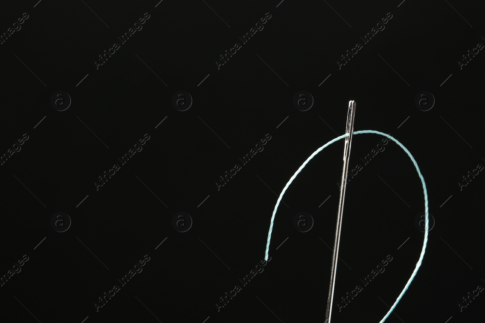 Photo of Needle with sewing thread on black background, closeup