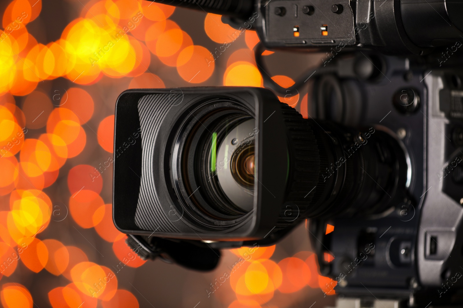 Photo of Modern video camera against blurred lights, closeup