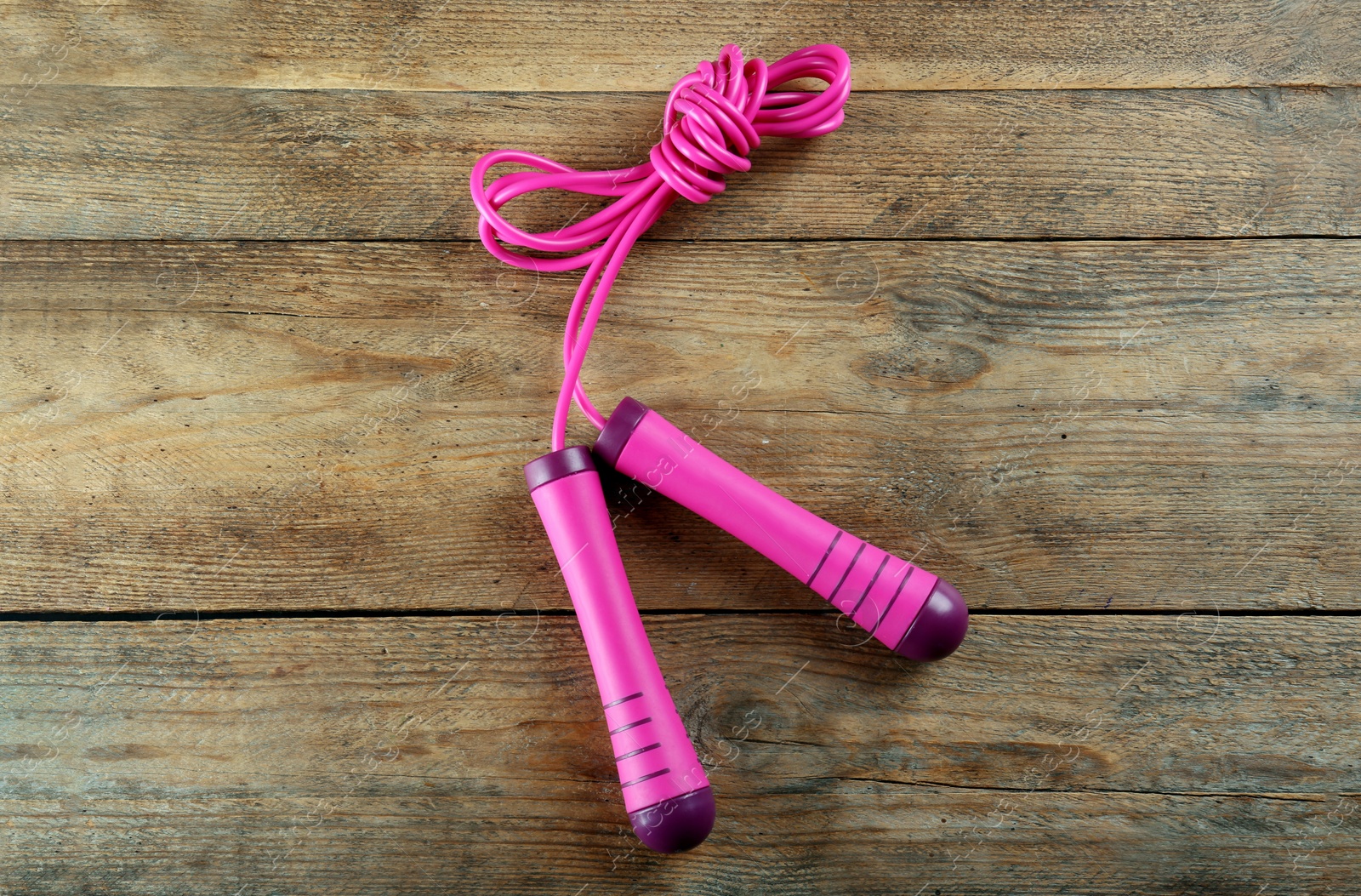 Photo of Skipping rope on wooden table, top view. Sports equipment