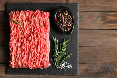 Photo of Raw ground meat, spices and rosemary on wooden table, top view. Space for text