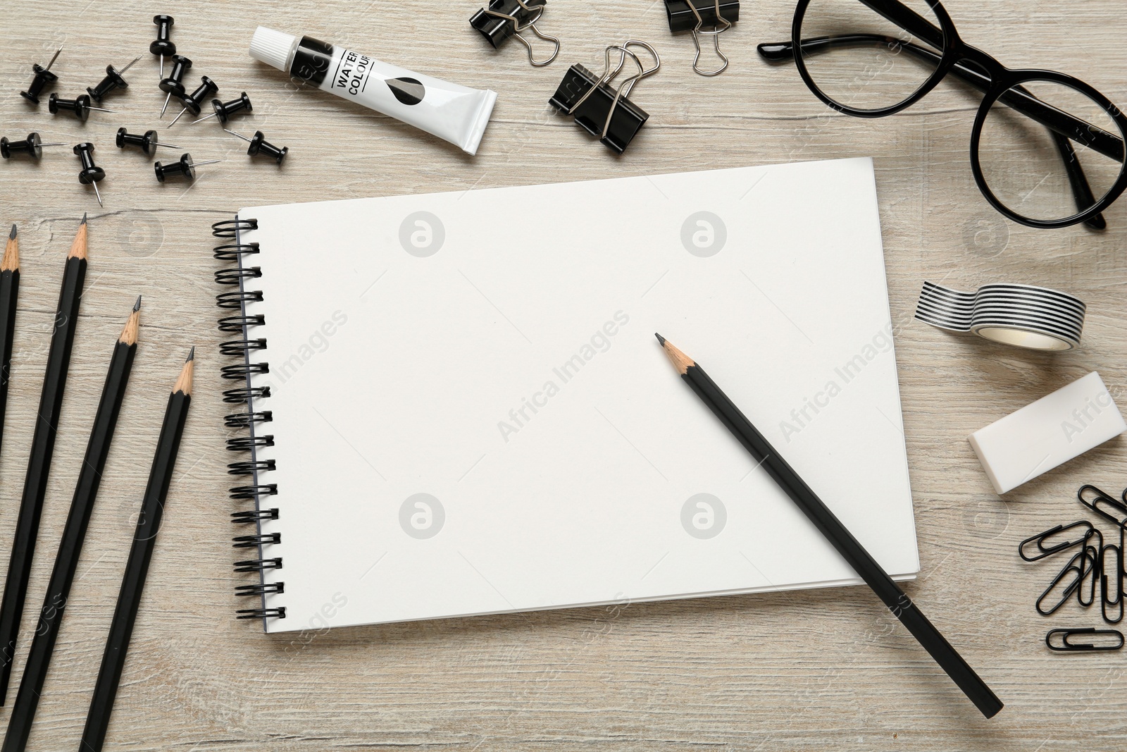 Photo of Flat lay composition with sketchbook and stationary on light wooden table