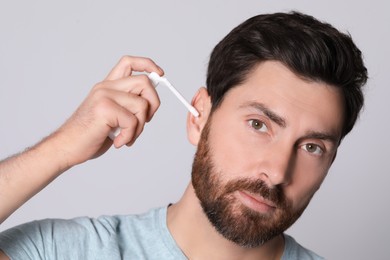 Photo of Man using ear spray on grey background