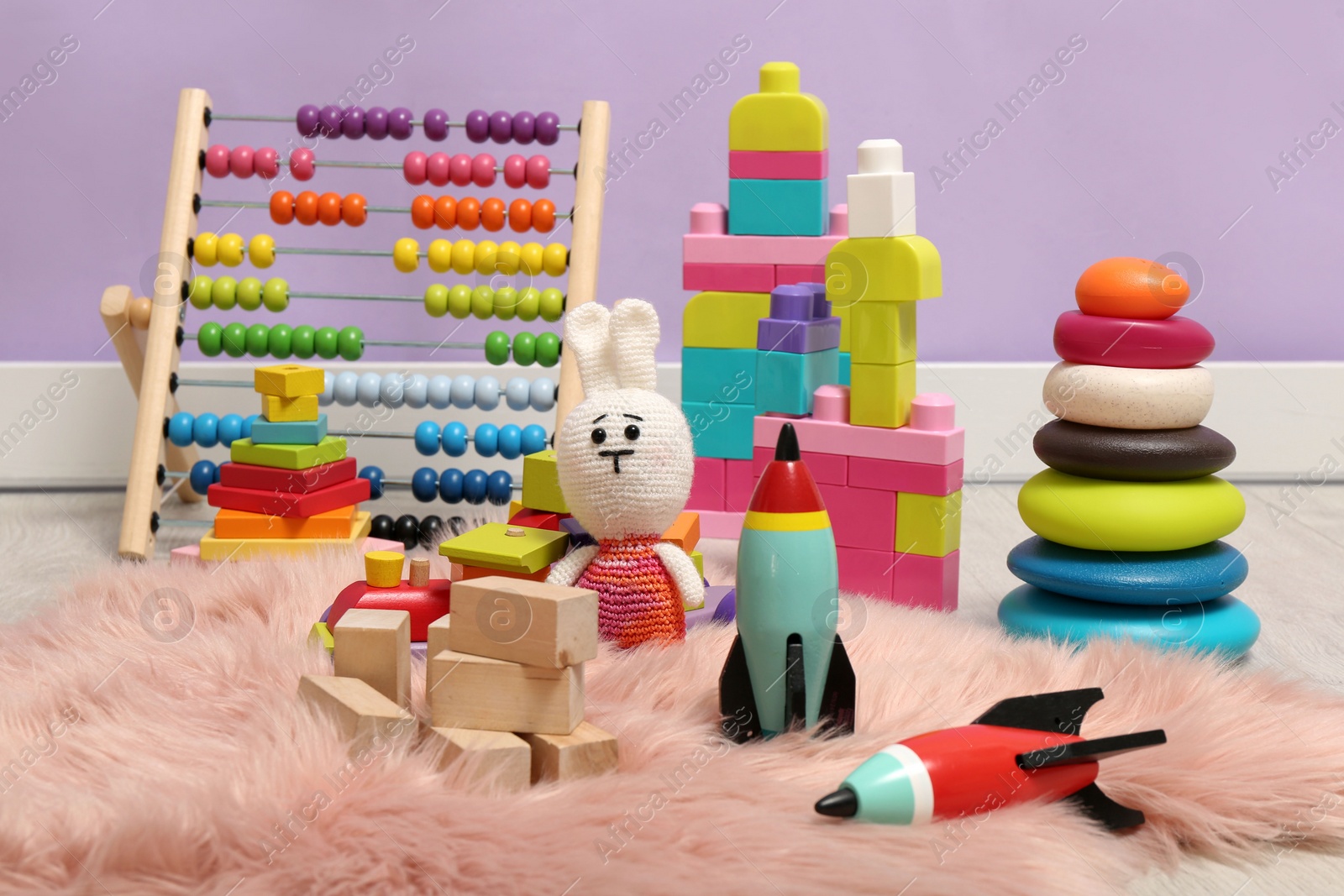 Photo of Set of different toys on rug near violet wall