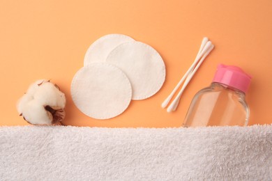 Photo of Flat lay composition with makeup remover and cotton flower on pale orange background