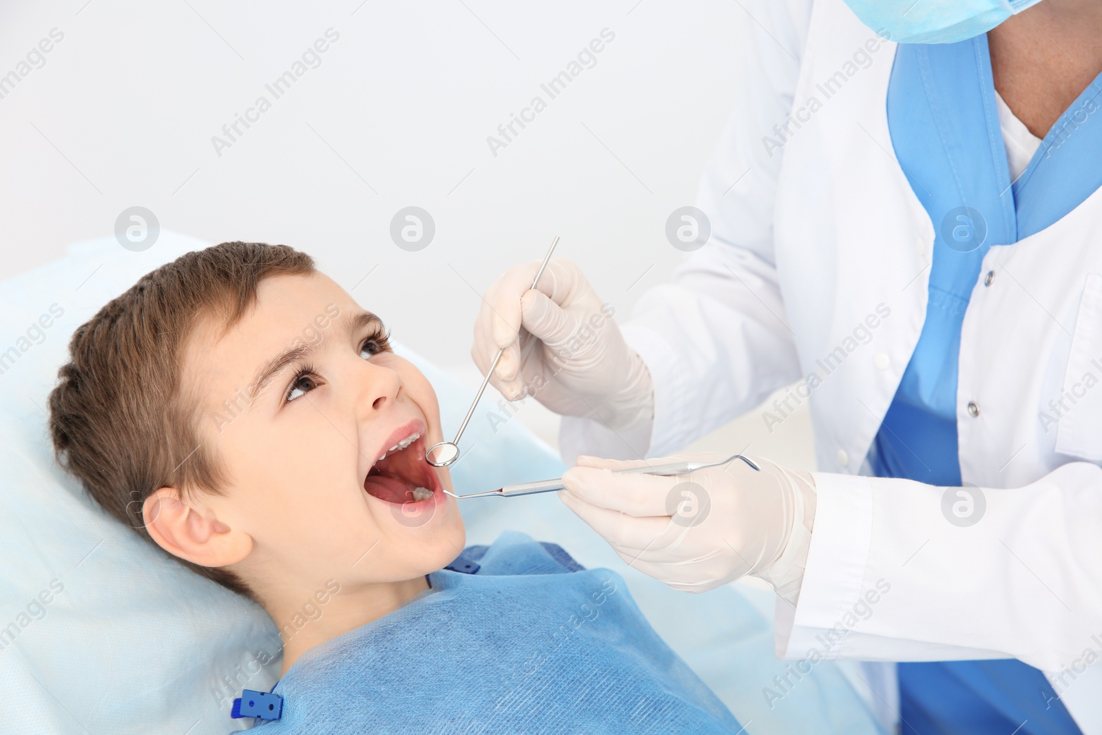 Photo of Dentist examining cute boy's teeth in modern clinic