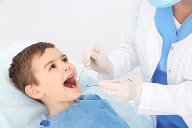 Photo of Dentist examining cute boy's teeth in modern clinic