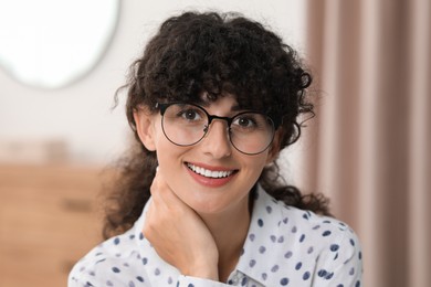 Photo of Portrait of beautiful woman with curly hair indoors. Attractive lady smiling and looking into camera