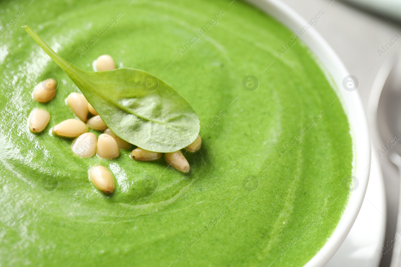 Photo of Bowl of healthy green soup with fresh spinach, closeup view