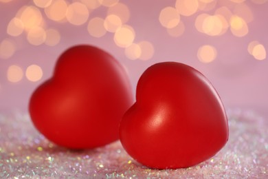 Red decorative hearts on glitter against blurred lights, closeup