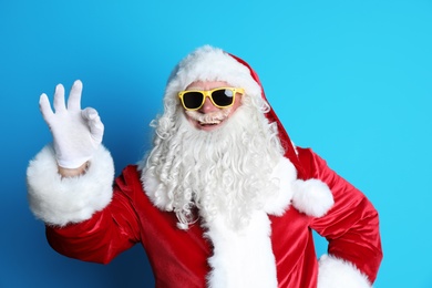 Authentic Santa Claus wearing sunglasses on color background