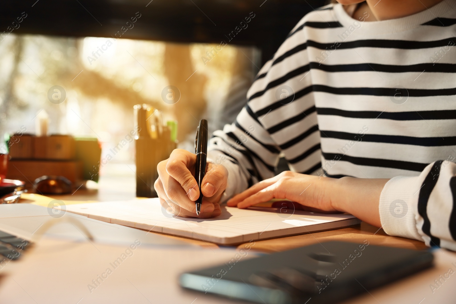 Photo of Young female student studying at table in cafe, closeup