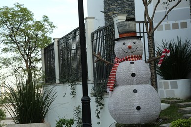 Photo of Funny snowman near house. Festive outdoor Christmas decoration