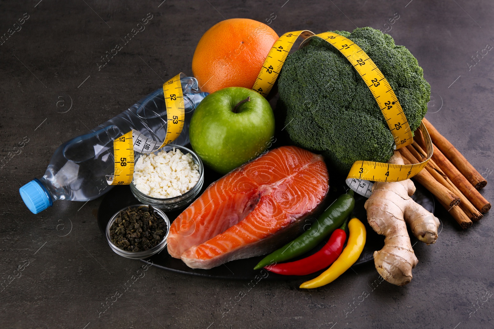 Photo of Metabolism. Different food products and measuring tape on grey table