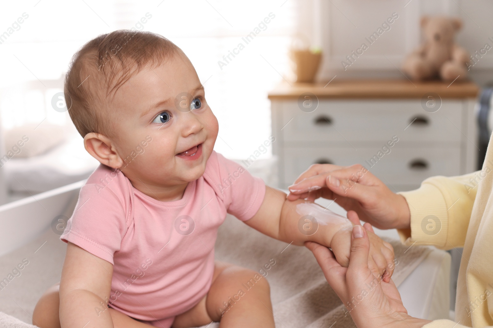 Photo of Mother applying body cream on her little baby at home, closeup