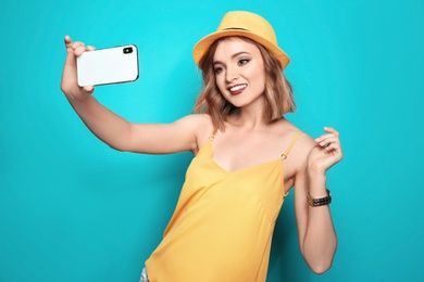 Photo of Beautiful young woman taking selfie on color background