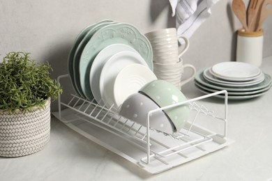 Photo of Many different clean dishware and houseplant on white table indoors