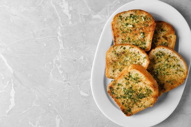 Photo of Slices of toasted bread with garlic and herbs on grey table, top view. Space for text