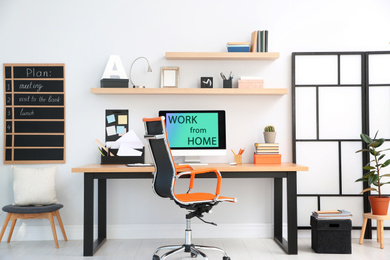 Modern computer with text WORK FROM HOME on table in office 