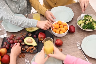 Photo of Friends eating vegetarian food at wooden table indoors, closeup