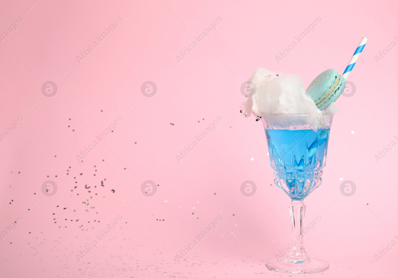 Photo of Cocktail with cotton candy in glass on pink background, space for text