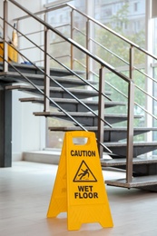 Photo of Safety sign with phrase Caution wet floor near stairs. Cleaning service