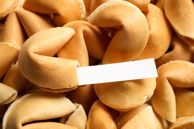 Photo of Fortune cookie with prediction on pile of biscuits, closeup