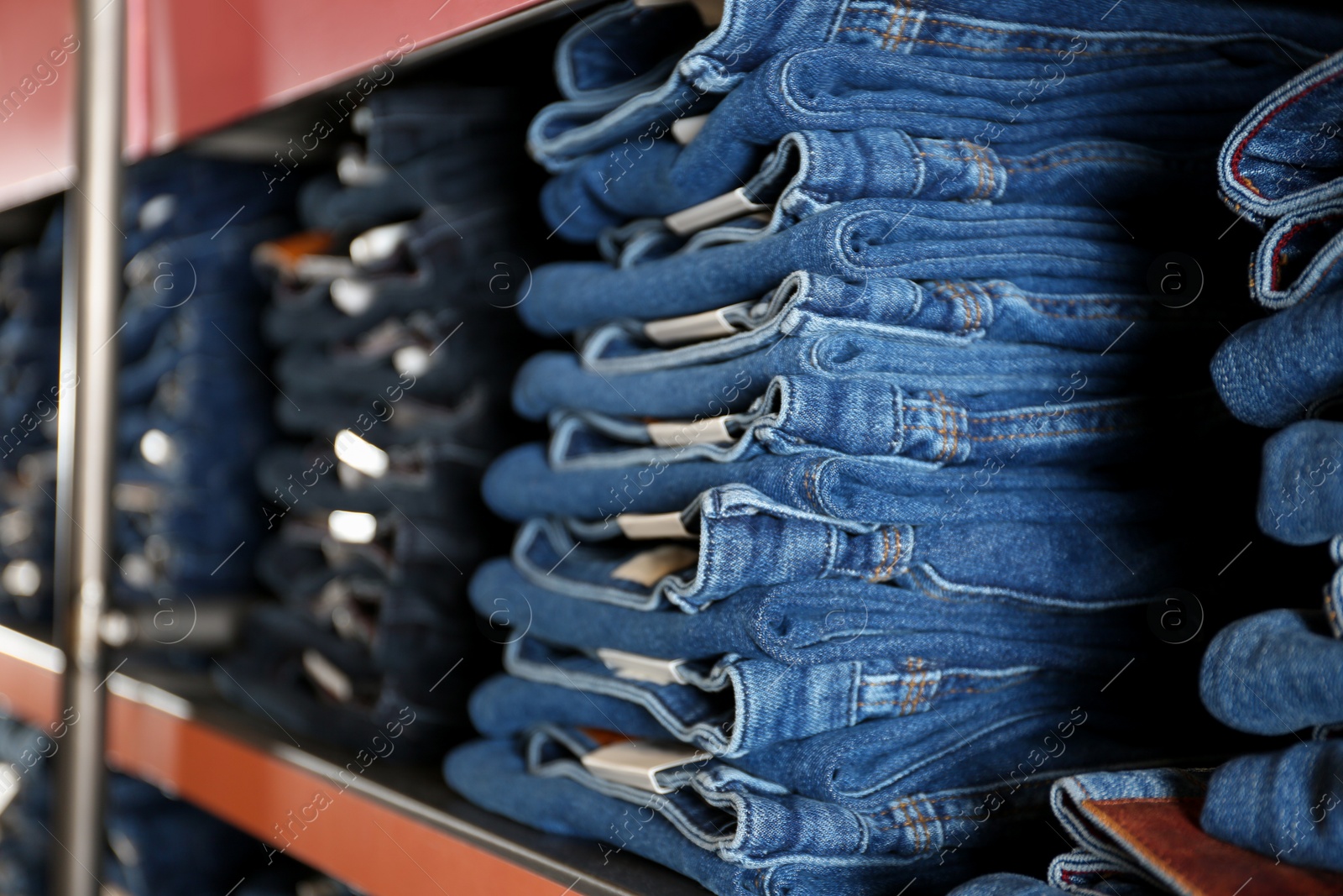 Photo of Collection of modern jeans on shelf in shop, closeup